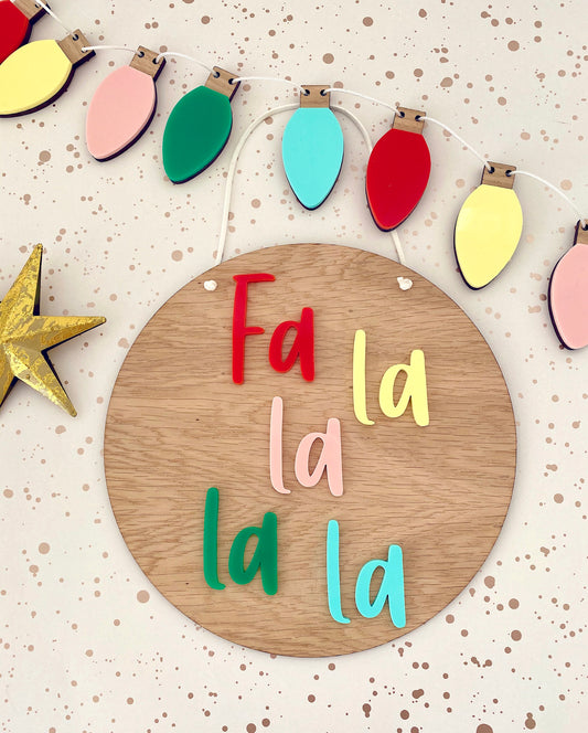 Fa la la la la wooden christmas plaque with colourful lettering and multicoloured christmas lights