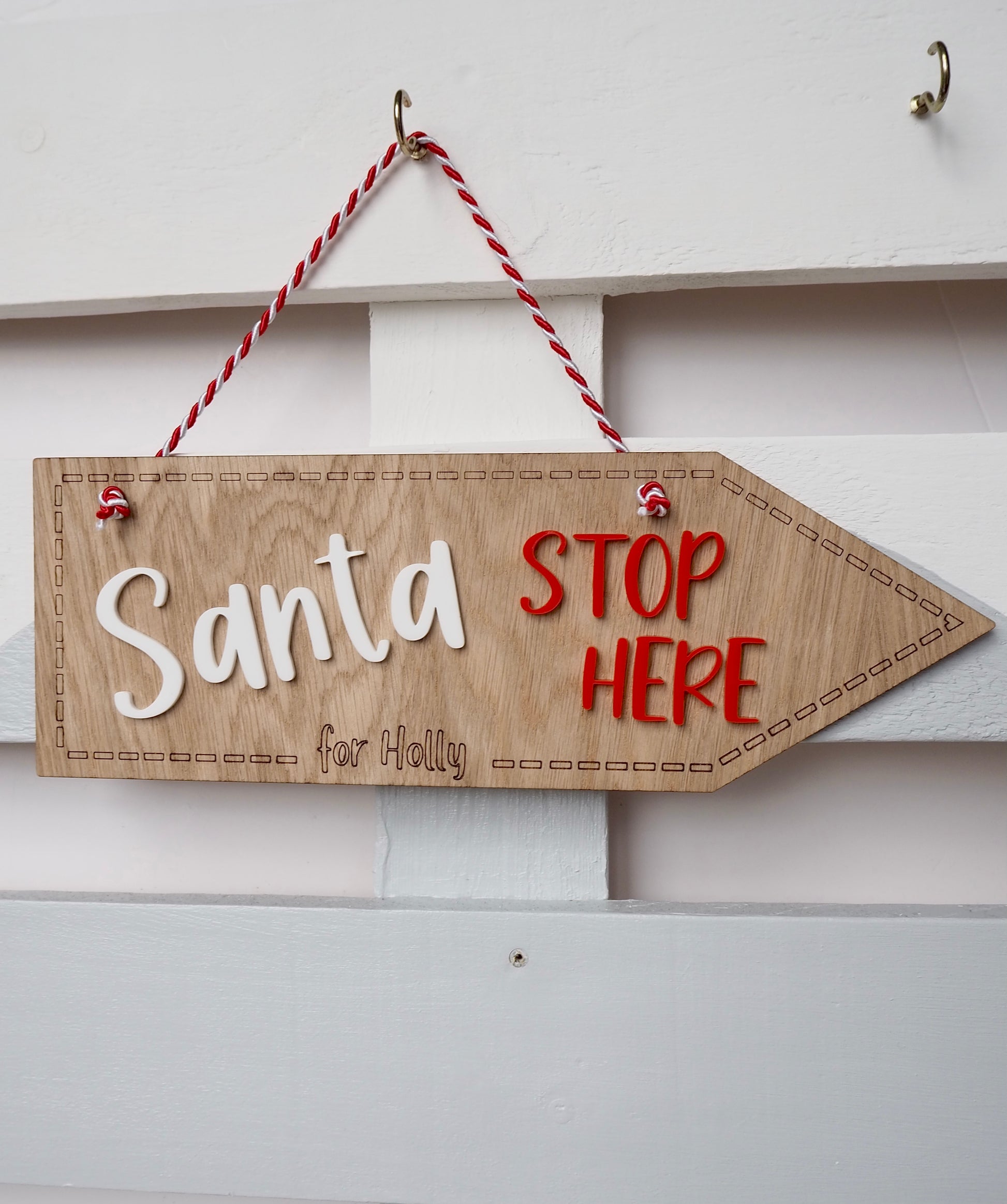 wooden hanging sign with Santa stop here in red and white acrylic. It is personalised with the name Holly engraved into the wood