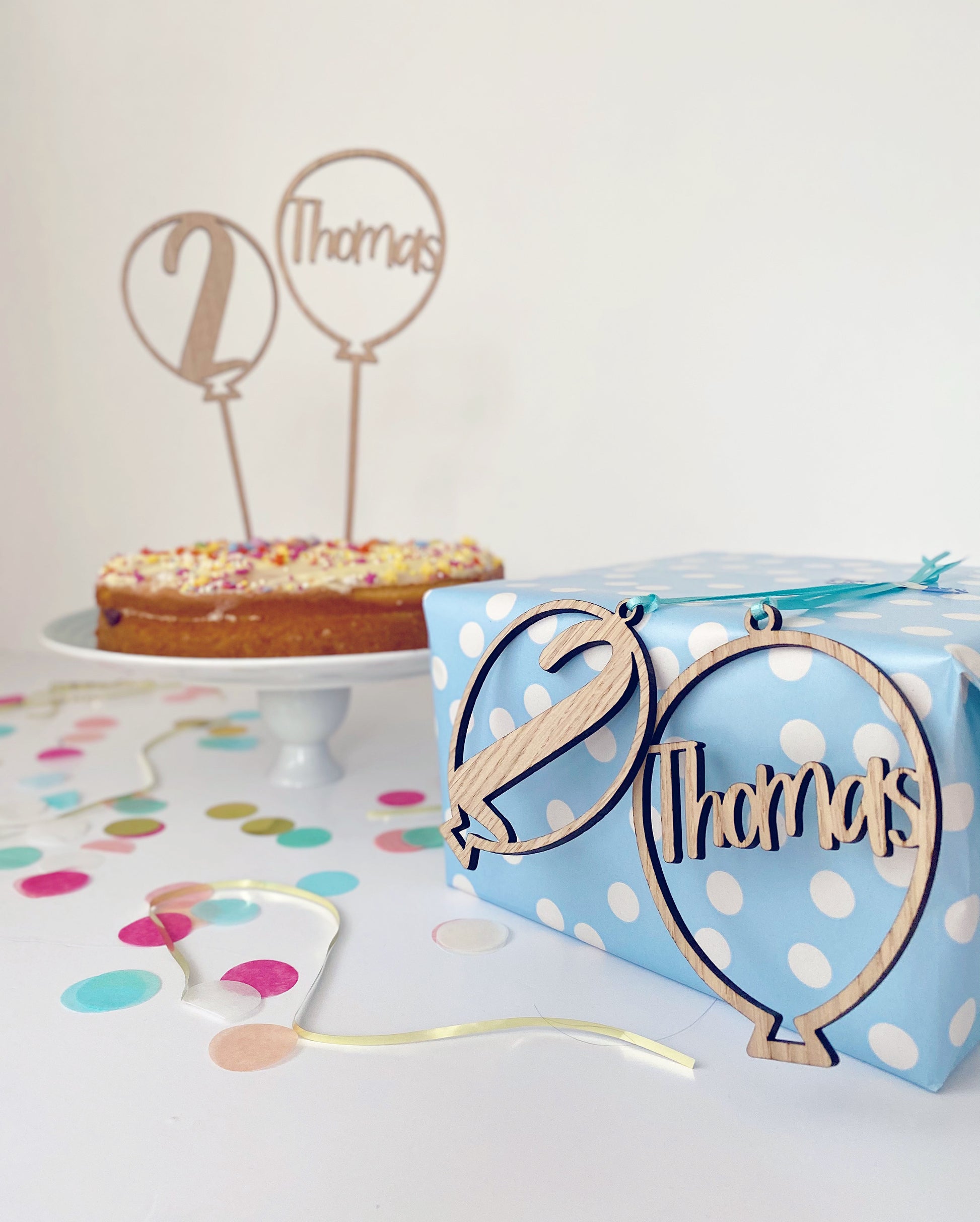 personalised birthday gift tags laser cut from wood in a balloon shape with the age and name cut out of the middle