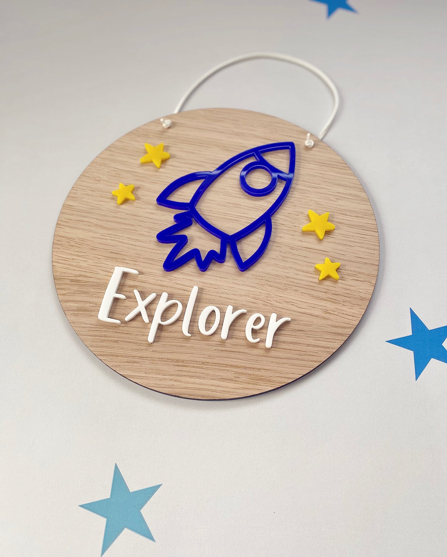 Wooden plaque with blue rocket and yellow stars. With the word Explorer written on