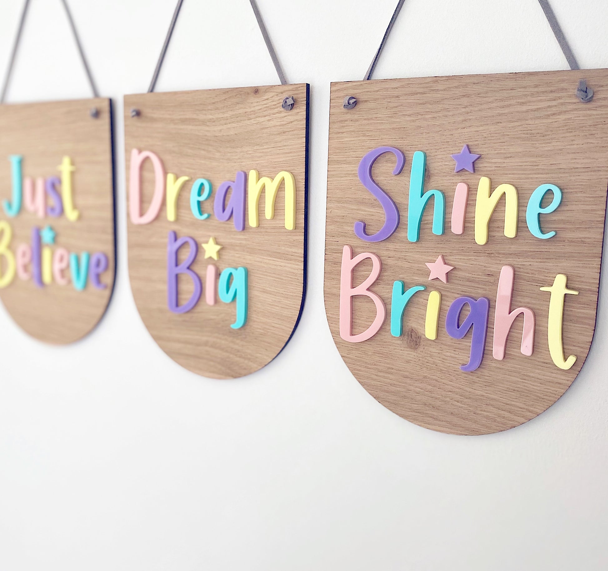 3 coordinating wooden plaques in a scalloped designs. Multicoloured pastel lettering on each saying - Just Believe, Dream Big and Shine Bright
