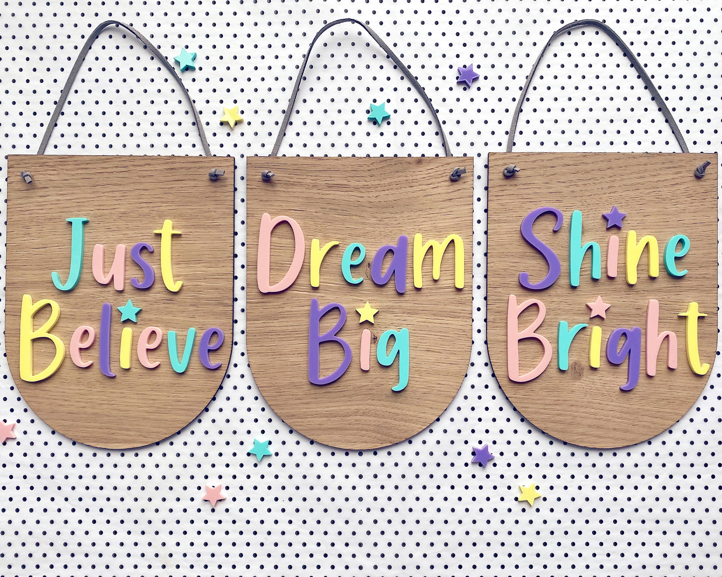 3 wooden wall hangings with the words Just Believe, Dream Big and Shine Bright in multicoloured pastel lettering